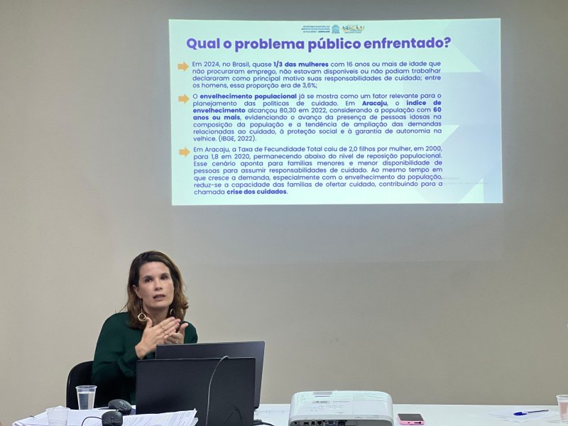 A coordenadora do PMC, Flávia Calumby, apresentou o andamento da elaboração do Plano Municipal de Cuidados